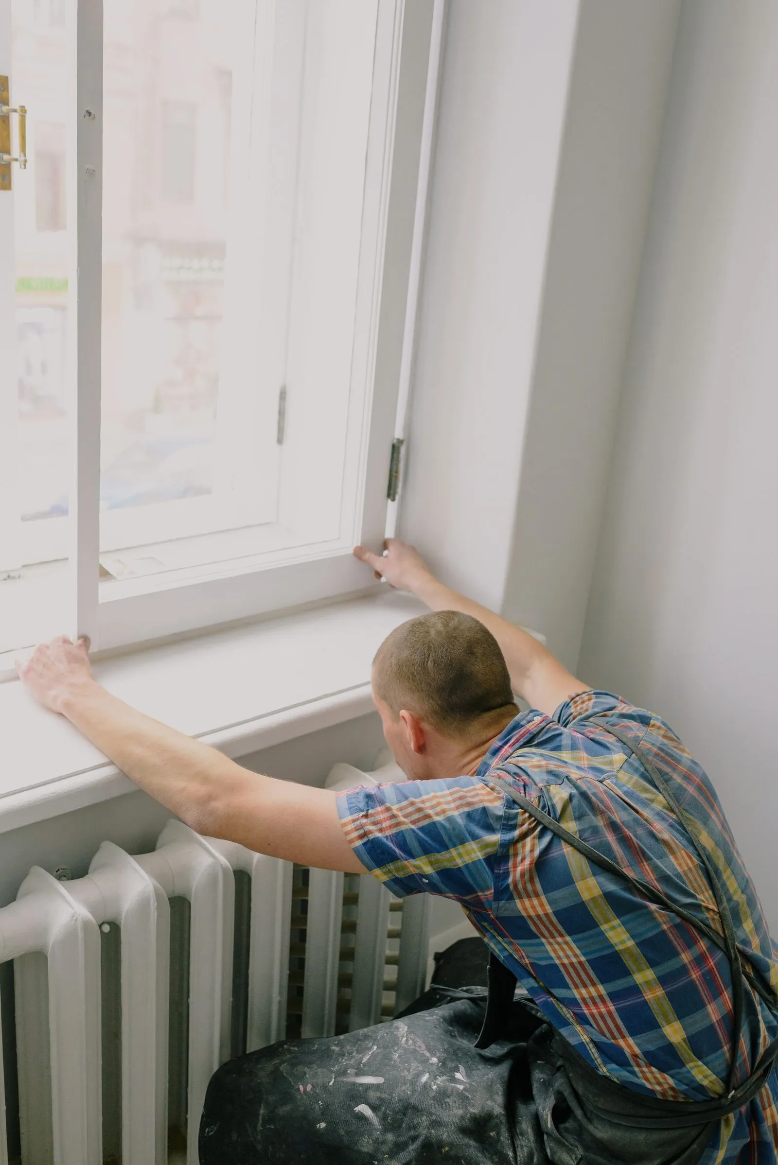 An engineer turning a radiator valve — the survey checks every radiator against the heat its room will need.